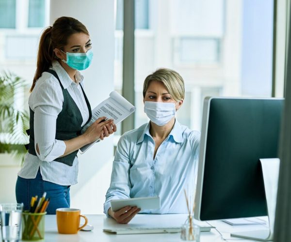 female-business-colleagues-with-face-masks-working-office-reading-email-computer_637285-5283